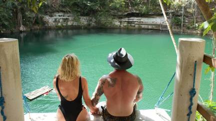 Couple sitting on a ledge on top of an open cenote