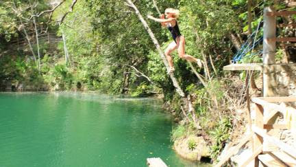 Girl jumping into a cenote from a ledge
