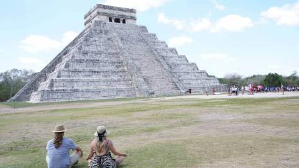Girls meditating in front of ancient Mayan pyramids of Chichen Itza