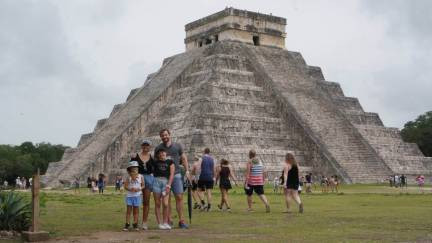 Family posing for a photo in front of a Chichen Itza pyramid